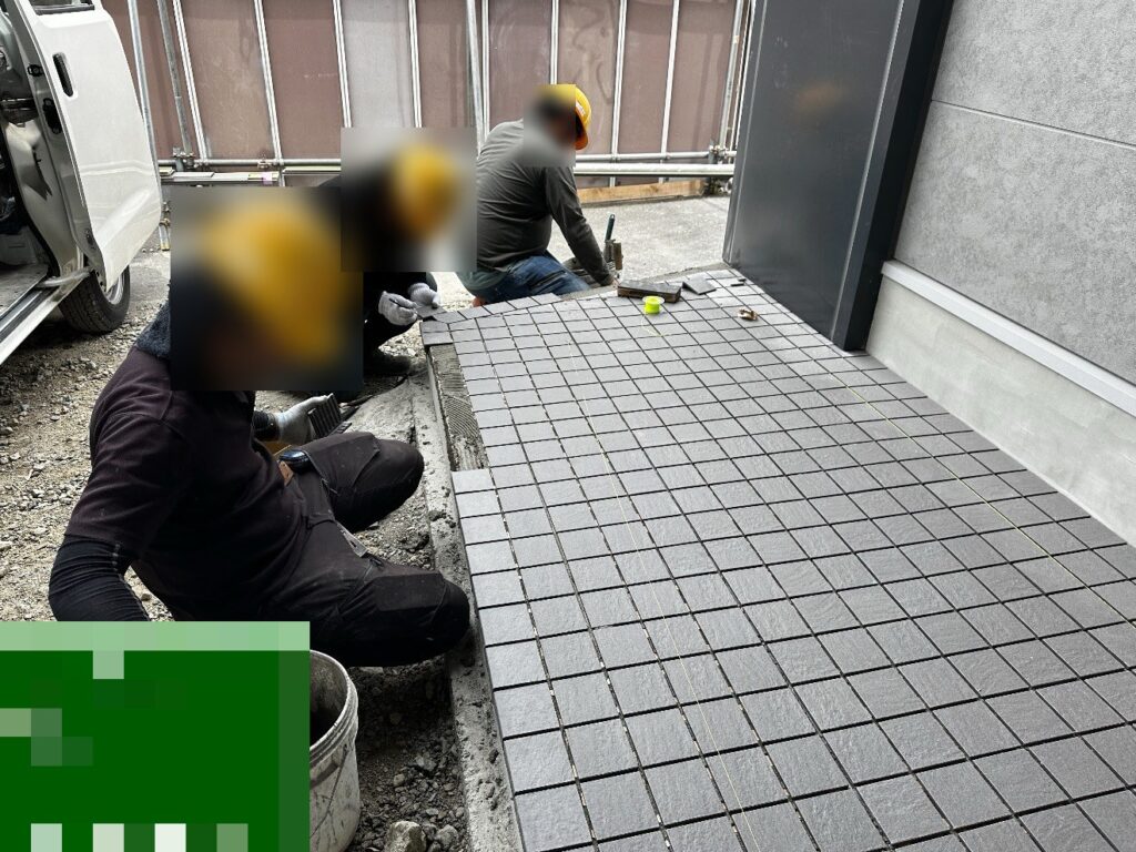 建物の外周の犬走りに床タイルを貼っている様子
